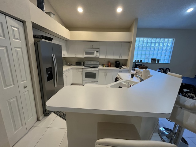 kitchen with white appliances, a kitchen breakfast bar, sink, and light tile patterned floors