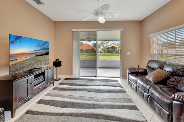 living room with ceiling fan, a textured ceiling, and light tile patterned flooring