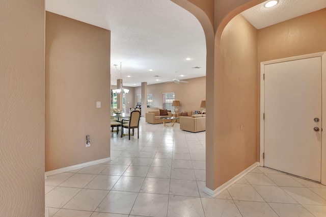 tiled entryway with ceiling fan with notable chandelier