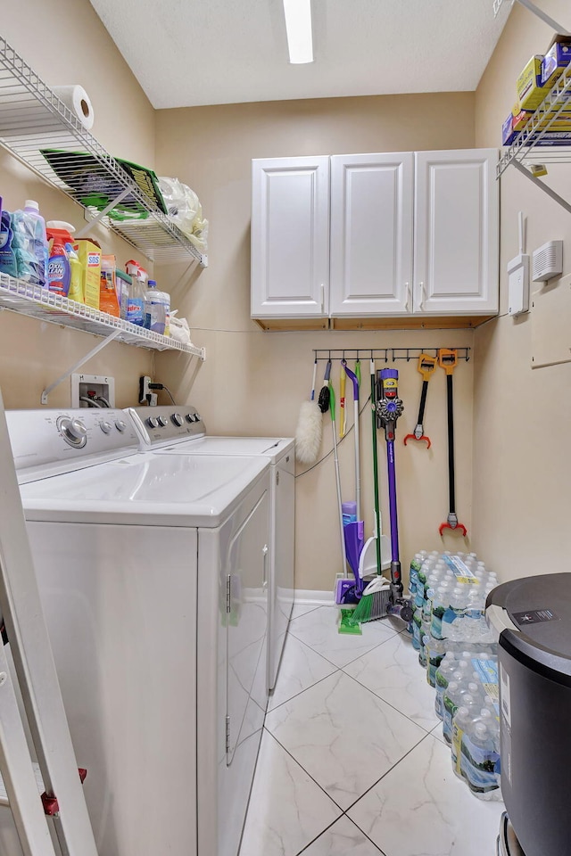 washroom featuring cabinets and washer and clothes dryer