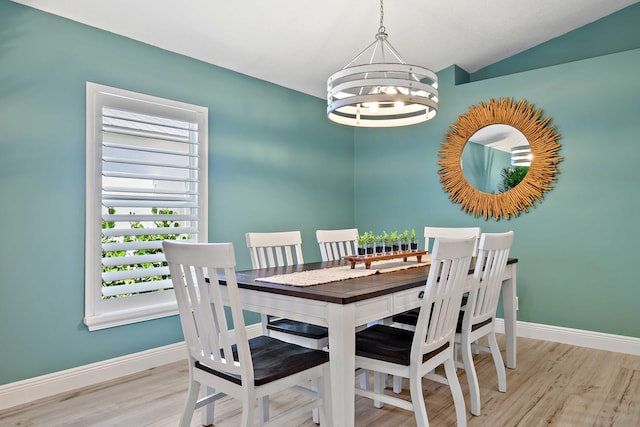 dining room with a chandelier, light hardwood / wood-style flooring, and vaulted ceiling