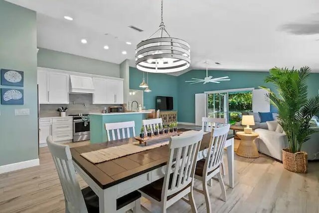 dining area featuring ceiling fan with notable chandelier, light hardwood / wood-style floors, and lofted ceiling