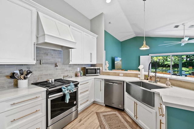 kitchen featuring premium range hood, stainless steel appliances, sink, pendant lighting, and lofted ceiling