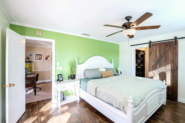 bedroom featuring ceiling fan, crown molding, a barn door, a spacious closet, and a closet