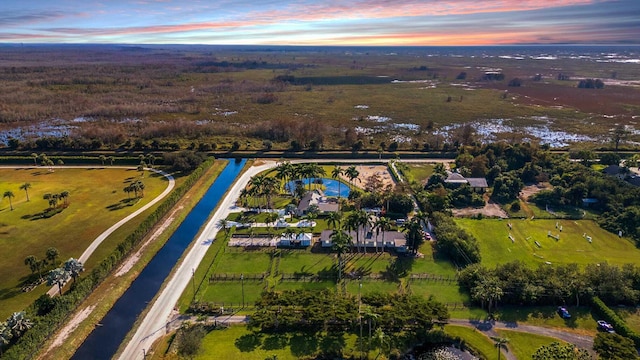 aerial view at dusk featuring a rural view and a water view