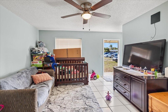 bedroom featuring ceiling fan, light tile patterned floors, and a textured ceiling