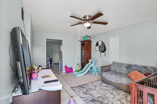 tiled living room with ceiling fan and a textured ceiling