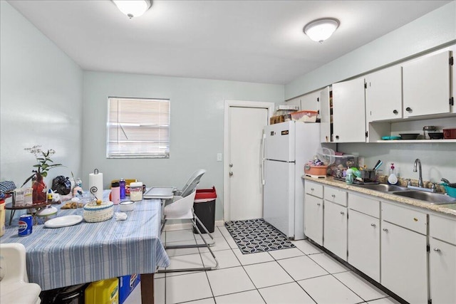 kitchen with white cabinets, light tile patterned floors, white fridge, and sink