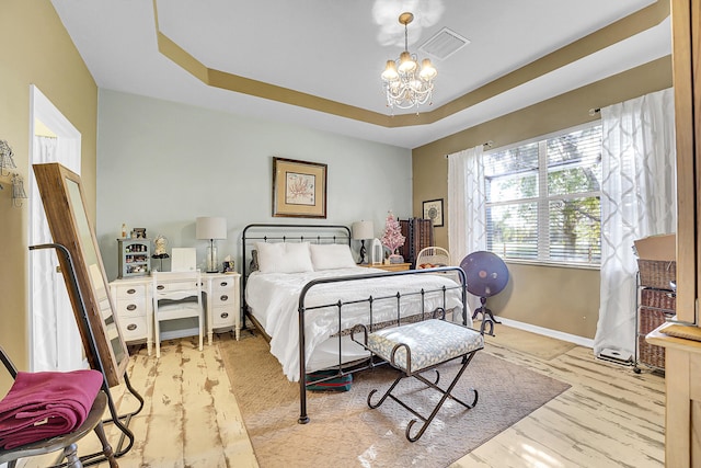 bedroom featuring an inviting chandelier and a raised ceiling