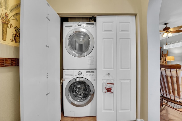 clothes washing area with a ceiling fan, stacked washer / drying machine, laundry area, and arched walkways