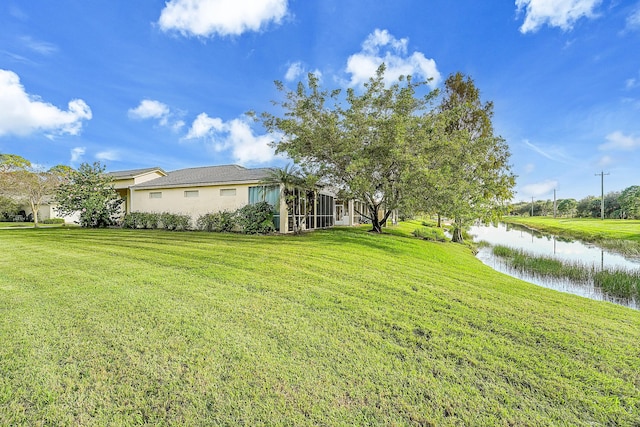 view of yard featuring a water view and a sunroom