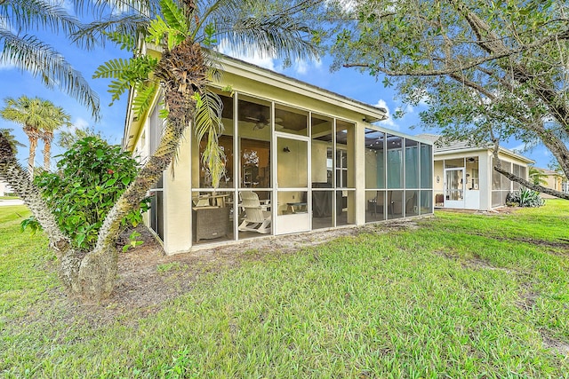 back of house with a lawn, a sunroom, and ceiling fan