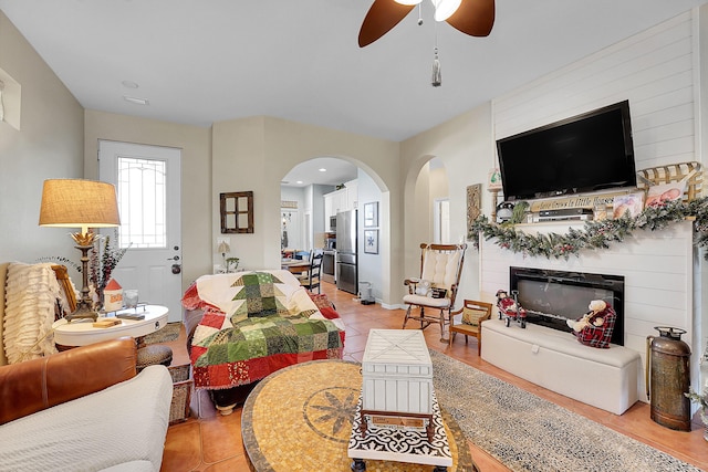 tiled living room featuring ceiling fan and a large fireplace