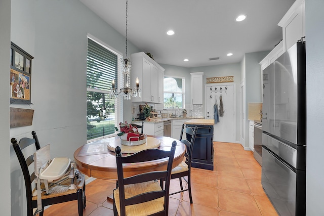 kitchen with decorative light fixtures, light tile patterned floors, backsplash, appliances with stainless steel finishes, and white cabinets