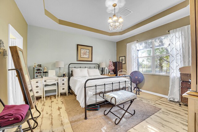 bedroom featuring a tray ceiling, visible vents, baseboards, and an inviting chandelier