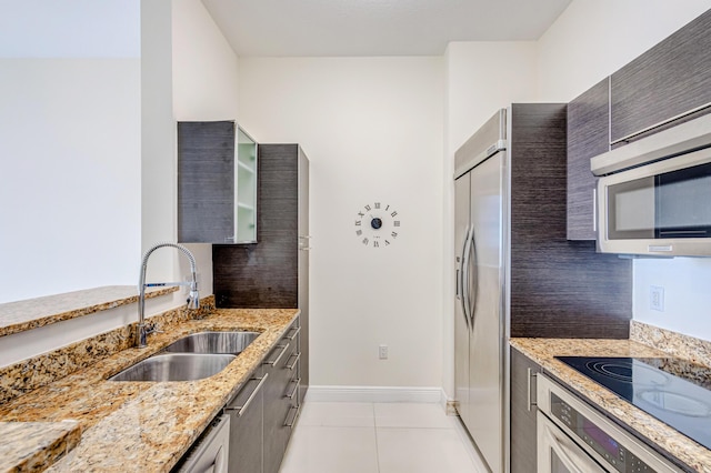 kitchen with backsplash, sink, light tile patterned floors, appliances with stainless steel finishes, and light stone counters