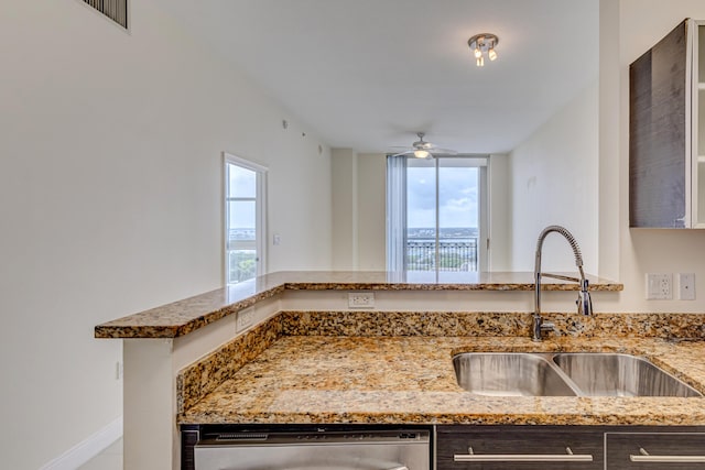 kitchen featuring stainless steel dishwasher, ceiling fan, sink, and stone counters