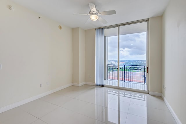 tiled spare room with ceiling fan and a wall of windows