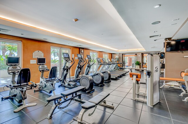 workout area with a tray ceiling and a wealth of natural light