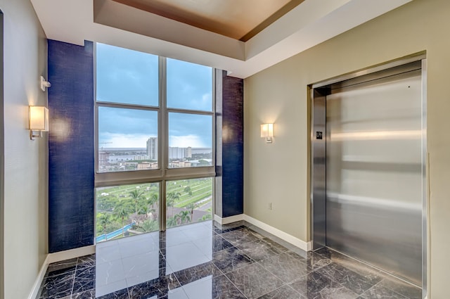 bathroom with a healthy amount of sunlight, elevator, and a tray ceiling