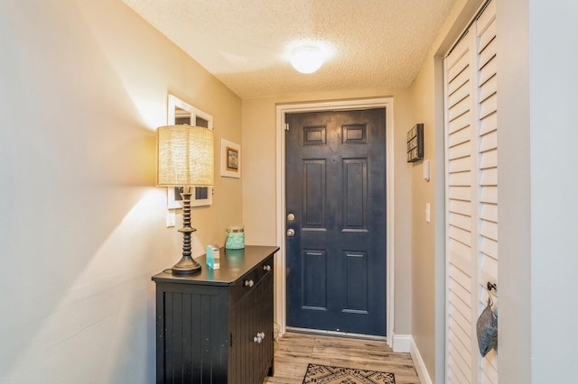 doorway to outside with a textured ceiling and light wood-type flooring