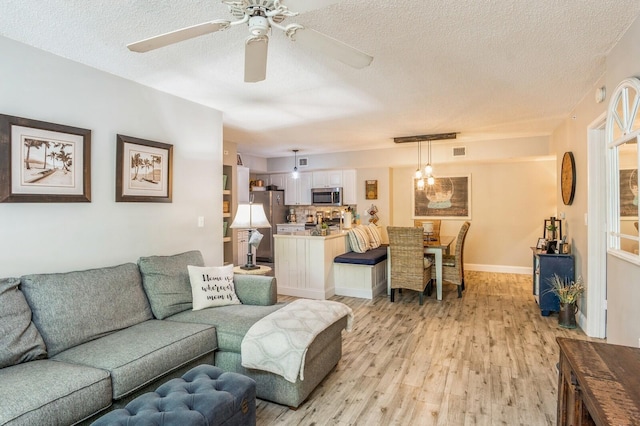 living room with ceiling fan, light hardwood / wood-style floors, and a textured ceiling