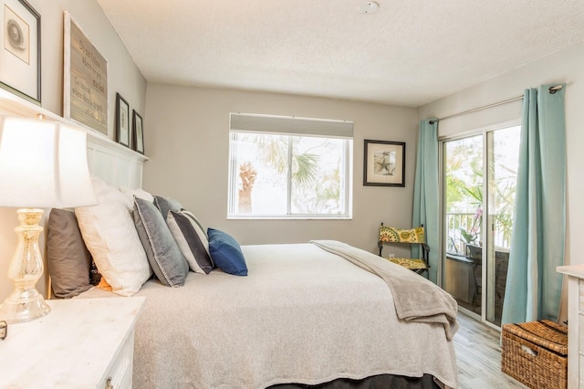 bedroom featuring light hardwood / wood-style floors, a textured ceiling, and access to outside