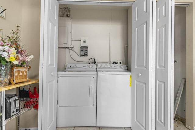 laundry area featuring light tile patterned floors, washing machine and dryer, and electric panel