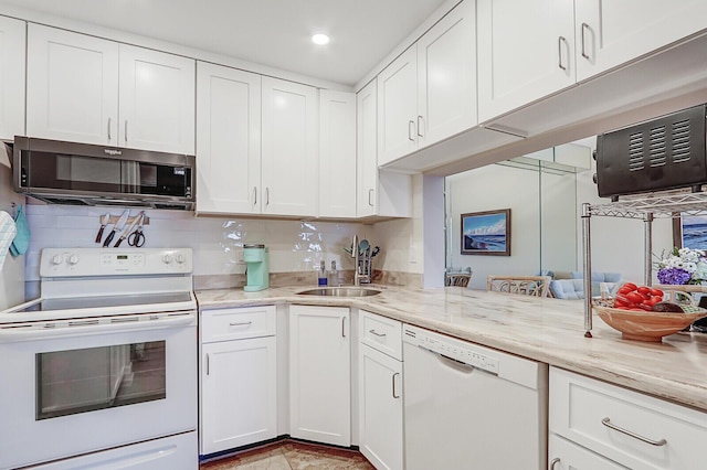 kitchen with light stone countertops, tasteful backsplash, white appliances, sink, and white cabinetry