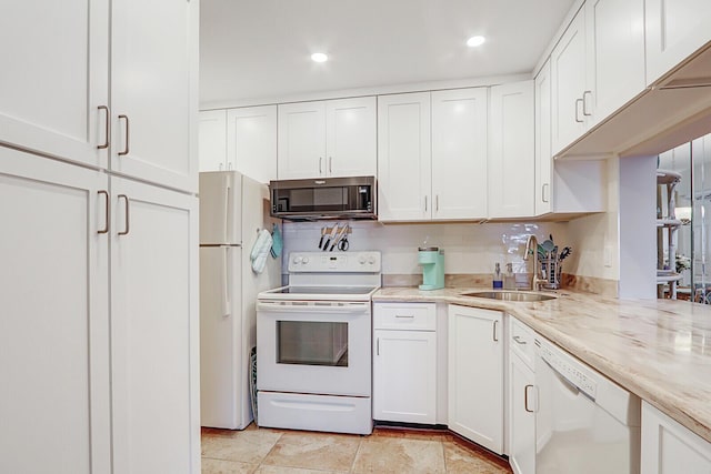 kitchen with white appliances, backsplash, white cabinets, sink, and light stone counters