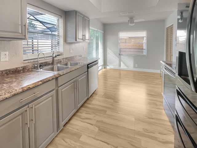 kitchen featuring gray cabinetry, ceiling fan, sink, stainless steel appliances, and decorative backsplash