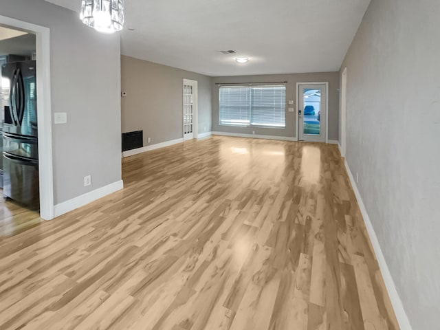 unfurnished living room with light hardwood / wood-style flooring and a chandelier