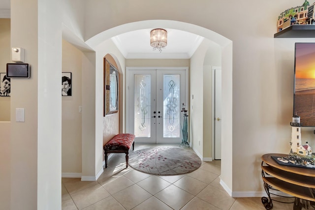 entrance foyer featuring french doors, light tile patterned floors, a chandelier, and ornamental molding