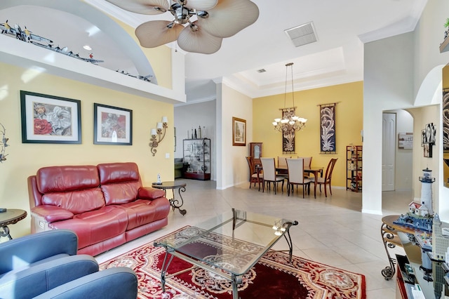 tiled living room with ceiling fan with notable chandelier, a raised ceiling, a towering ceiling, and crown molding