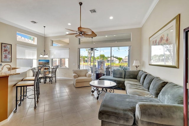 tiled living room with ceiling fan with notable chandelier and ornamental molding