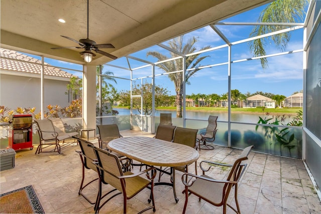 sunroom / solarium featuring ceiling fan and a water view