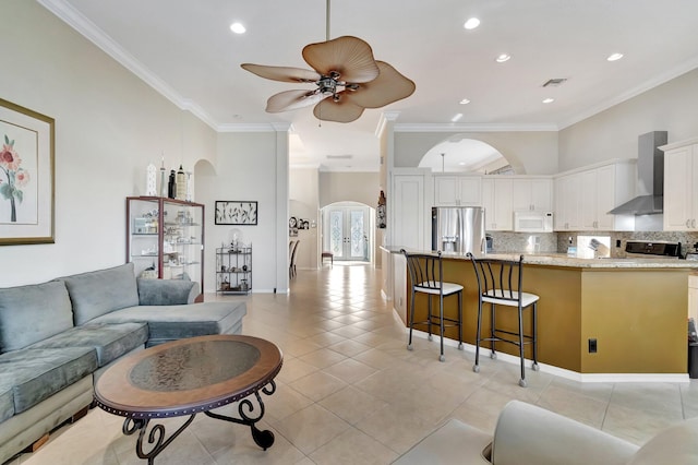 living room with a high ceiling, ceiling fan, ornamental molding, and light tile patterned flooring