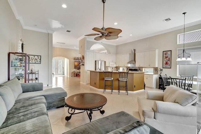 tiled living room with ceiling fan with notable chandelier, plenty of natural light, and ornamental molding