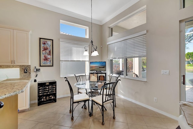 tiled dining room featuring a healthy amount of sunlight, wine cooler, crown molding, and a notable chandelier