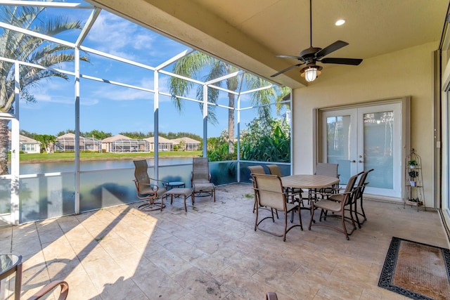 view of patio with a lanai, ceiling fan, french doors, and a water view