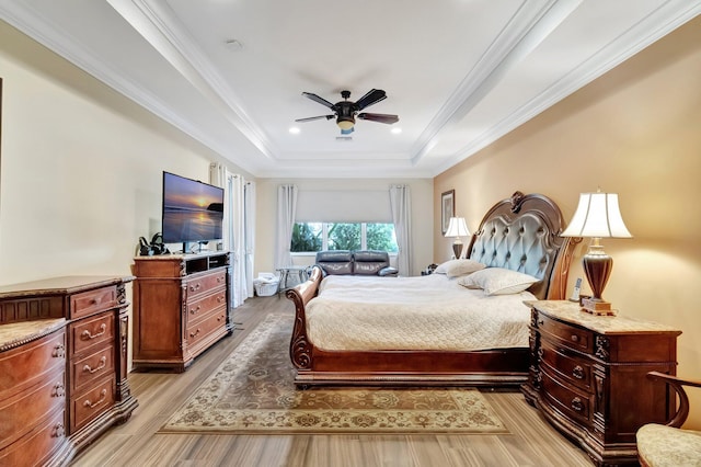 bedroom featuring light hardwood / wood-style flooring, a raised ceiling, ceiling fan, and crown molding