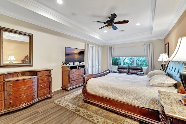 bedroom featuring hardwood / wood-style flooring, a raised ceiling, ceiling fan, and ornamental molding