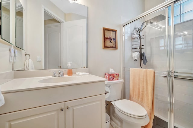 bathroom with an enclosed shower, vanity, and toilet