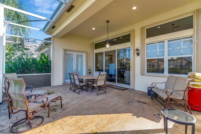 view of patio with ceiling fan and glass enclosure