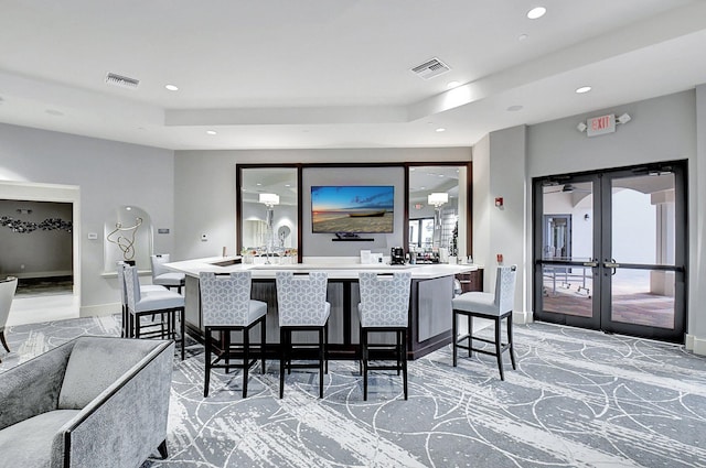 dining area featuring french doors, indoor bar, and a raised ceiling