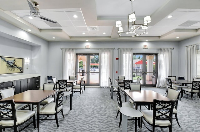 dining room featuring ceiling fan with notable chandelier, dark carpet, a wealth of natural light, and french doors