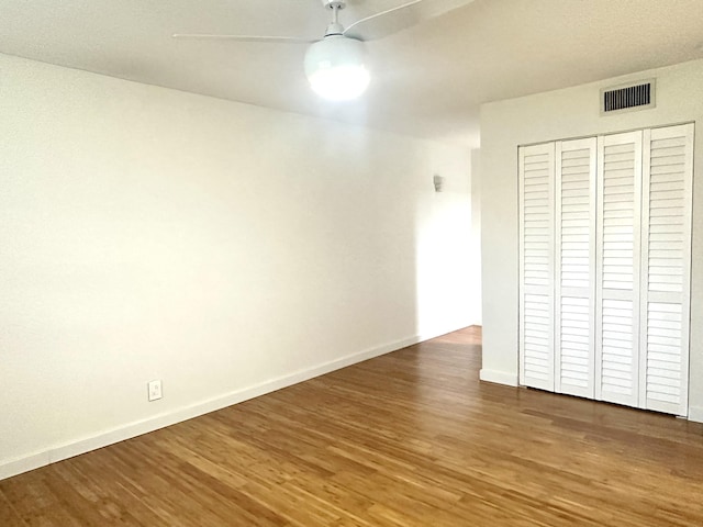 unfurnished bedroom featuring ceiling fan, dark hardwood / wood-style flooring, and a closet