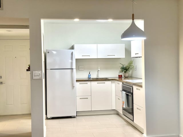 kitchen with sink, white cabinets, white fridge, oven, and hanging light fixtures