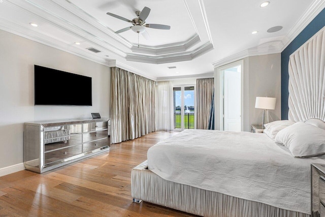 bedroom featuring ceiling fan, crown molding, access to outside, a tray ceiling, and hardwood / wood-style flooring