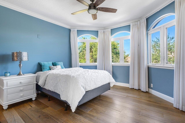 bedroom featuring a textured ceiling, hardwood / wood-style flooring, ceiling fan, and ornamental molding